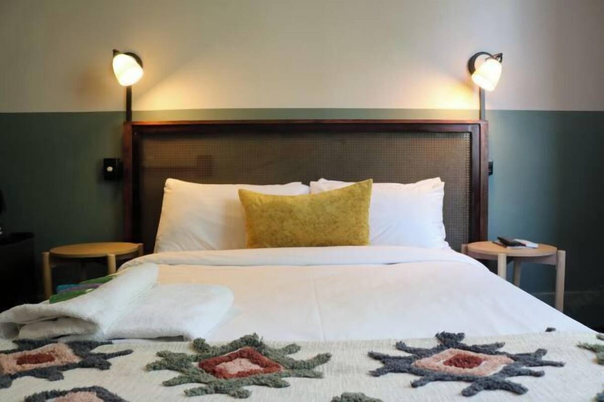 A neatly made bed with a patterned blanket, two bedside lamps, and a headboard.