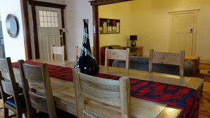 A dining area with a wooden table, chairs, and a vase. There is a door and a window in the background. - Glenelg Gateway Apartments (Glenelg)