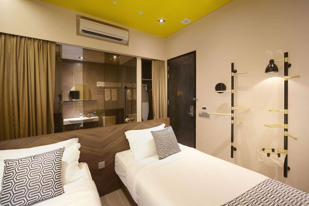 Hotellihuone, jossa on kaksi sänkyä, suuri peili, vaatekaappi ja seinään kiinnitetty valaisin.