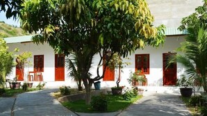 A courtyard with a white building, red doors, and potted plants. - Diem Lien Guesthouse (Mui Ne)