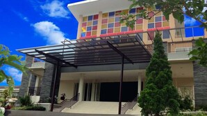 A modern two-story building with a glass entrance and a covered outdoor area. - Casa Monte Rosa Hotel (Cipanas)