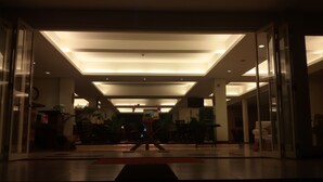 A spacious lobby with a modern ceiling design, glass doors, and a central area with a red mat. - Casa Monte Rosa Hotel (Cipanas)