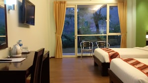 A hotel room with a bed, a desk with a chair, a TV, and a window with curtains. - Casa Monte Rosa Hotel (Cipanas)