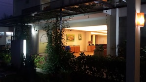A modern building with a covered outdoor area, a piano, and a dining table with chairs. - Casa Monte Rosa Hotel (Cipanas)