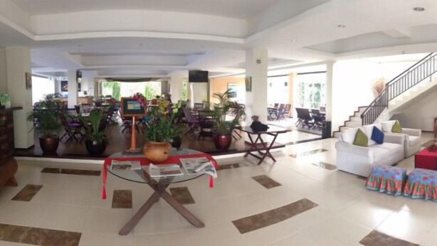 A spacious living area with a glass coffee table, multiple seating options, and a staircase leading to an upper level. - Casa Monte Rosa Hotel (Cipanas)