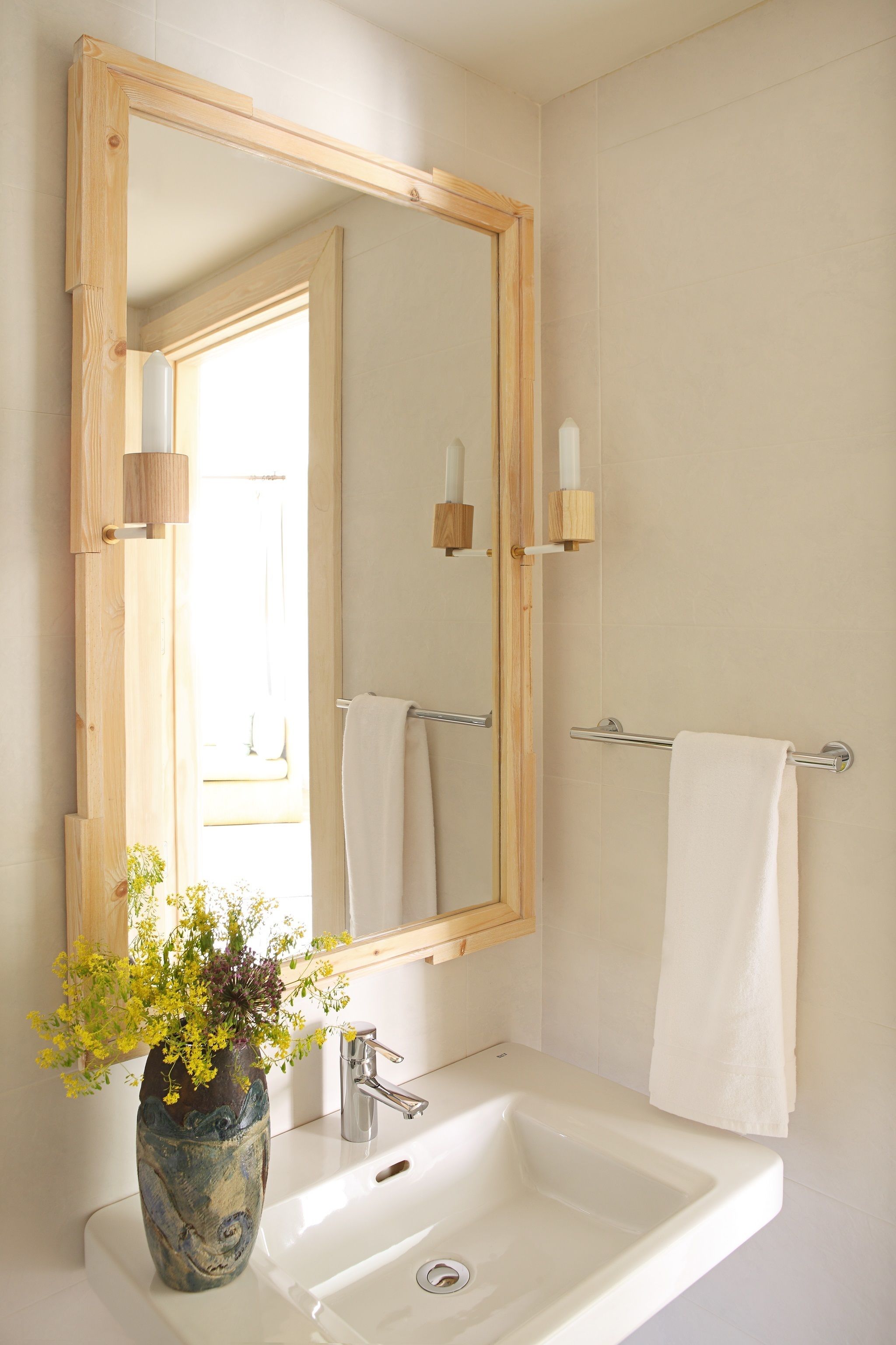 A bathroom with a wooden-framed mirror, a white sink, and a towel rack.