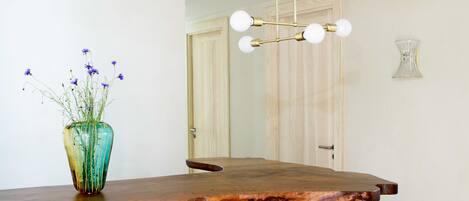 A reception desk with a wooden top, a vase with flowers, and a modern chandelier.