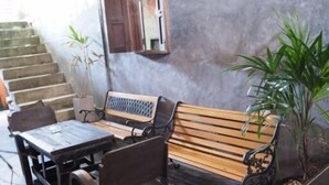 Un espacio de estar con un banco de madera y una mesa, rodeado de sillas.