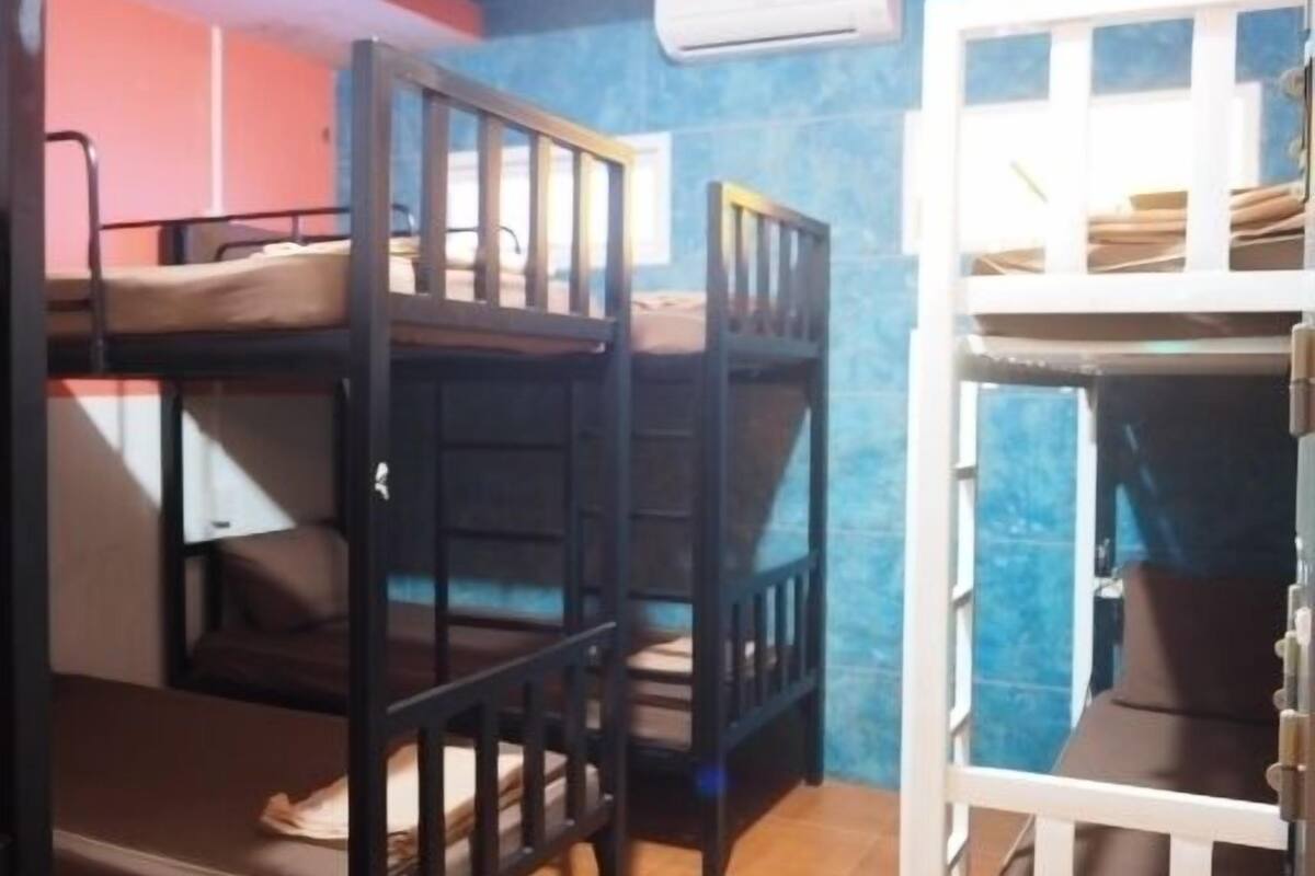 Una habitación con dos literas, una con estructura blanca y la otra con estructura oscura.