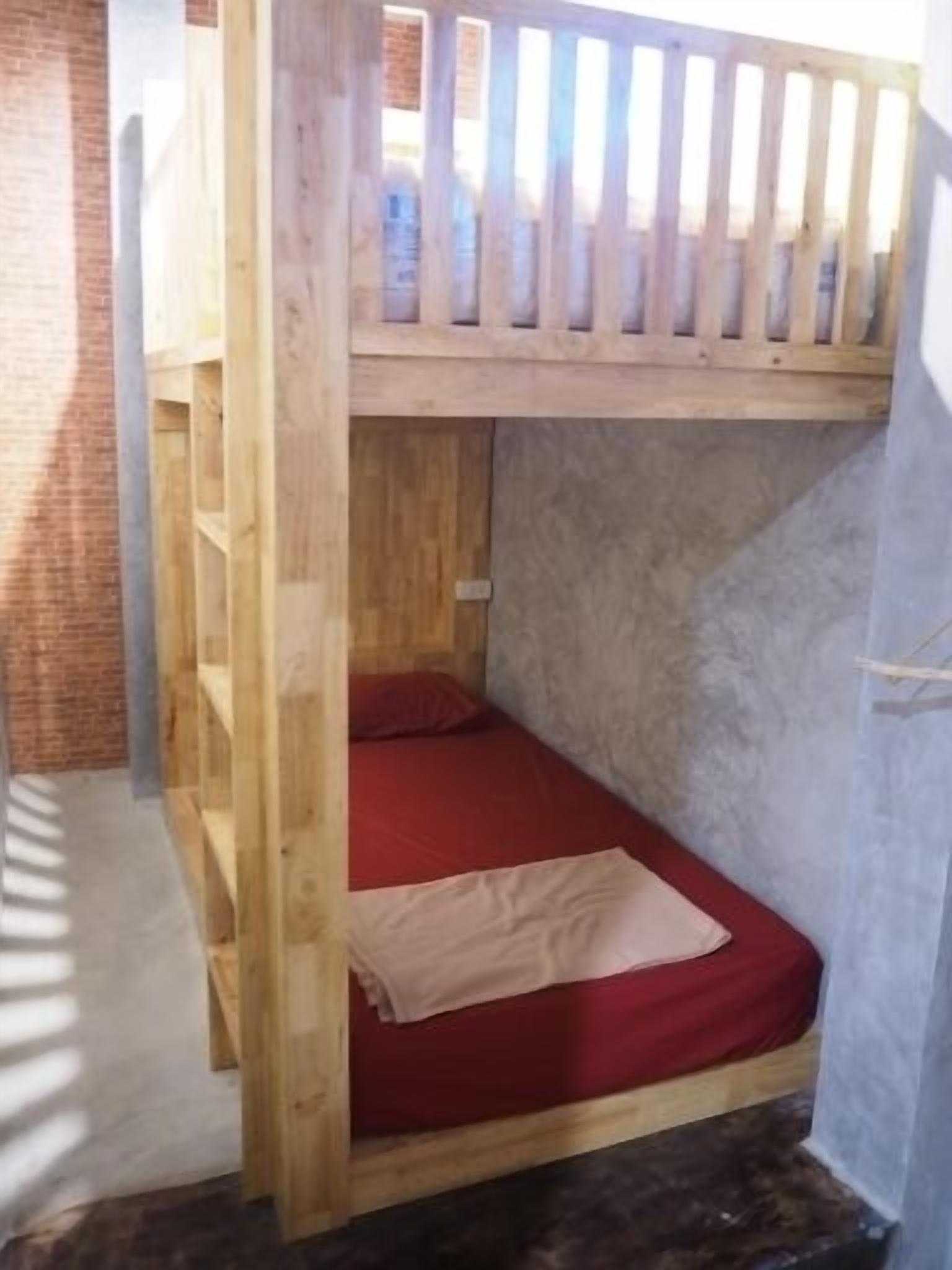 Un lit superposé avec un matelas rouge et une tête de lit en bois.