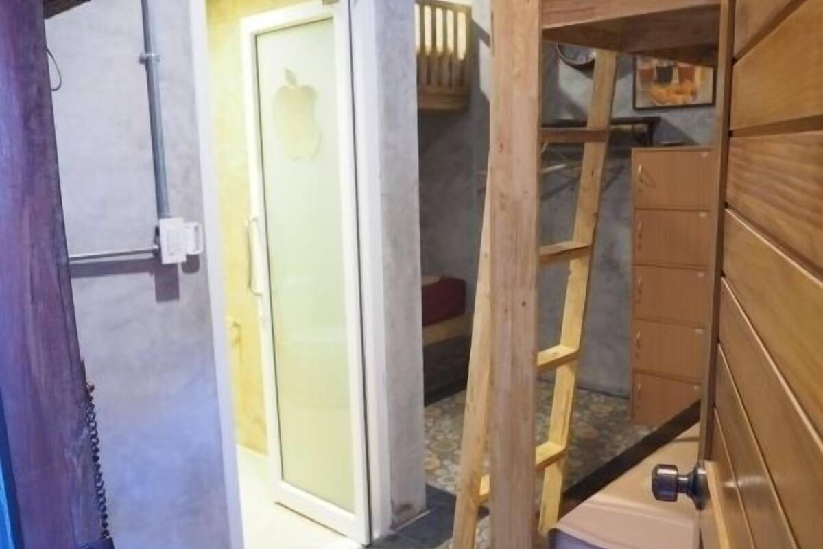 Una habitación con una escalera de madera, una puerta con un panel de vidrio esmerilado y un suelo de baldosas.