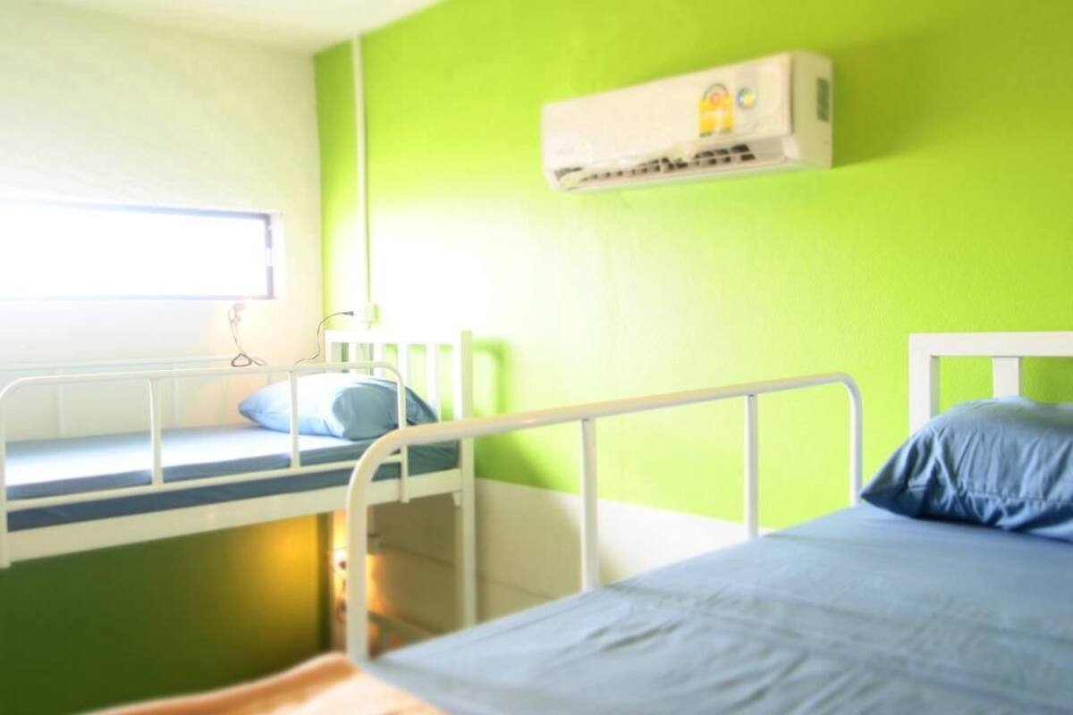 Una habitación con literas, una ventana y un equipo de aire acondicionado.