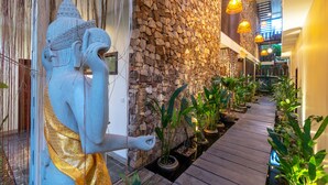 A statue of a deity in a corridor with a stone wall and potted plants. - King Rock Boutique Hotel (Siem Reap)