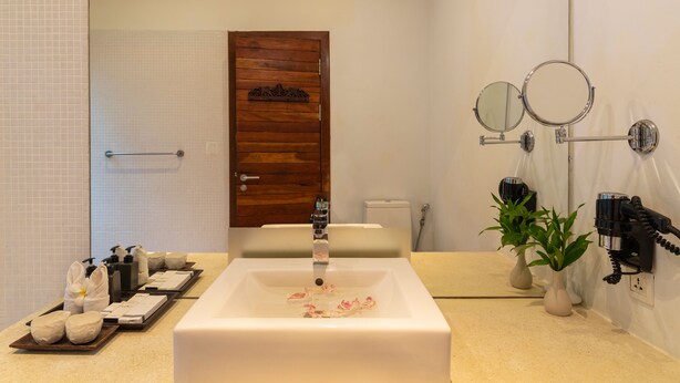 A modern bathroom with a large white sink, wooden door, and two wall-mounted mirrors. - King Rock Boutique Hotel (Siem Reap)