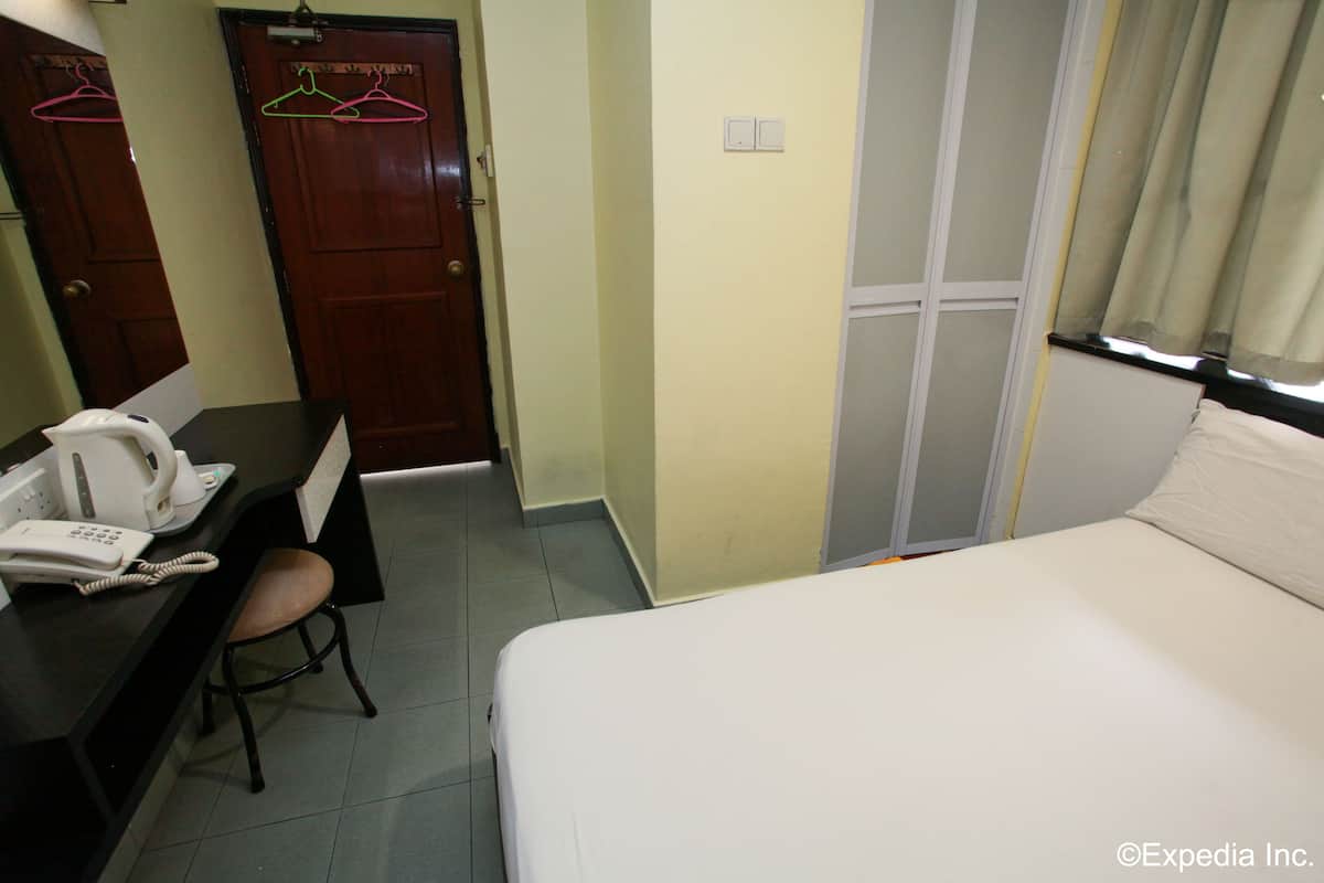 A hotel room with a bed, a desk with a telephone, and a chair.