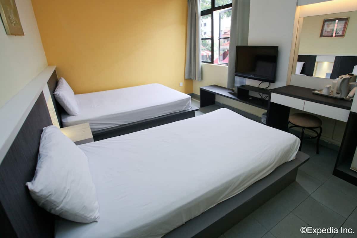 A hotel room with two single beds, a desk with a computer, a TV, and a chair.
