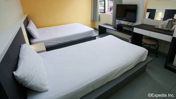 A hotel room with two single beds, a desk with a computer, a TV, and a chair.