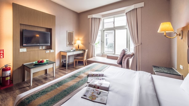 A hotel room with a bed, desk, TV, lamp, and a window with curtains. - Travel Road Hotel (Hualien City)