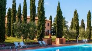 Una piscina con sillones de descanso y un edificio al fondo.