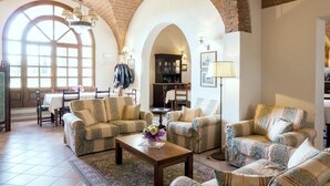 Amplia sala de estar con techos altos en arco, chimenea y comedor con mesa y sillas.