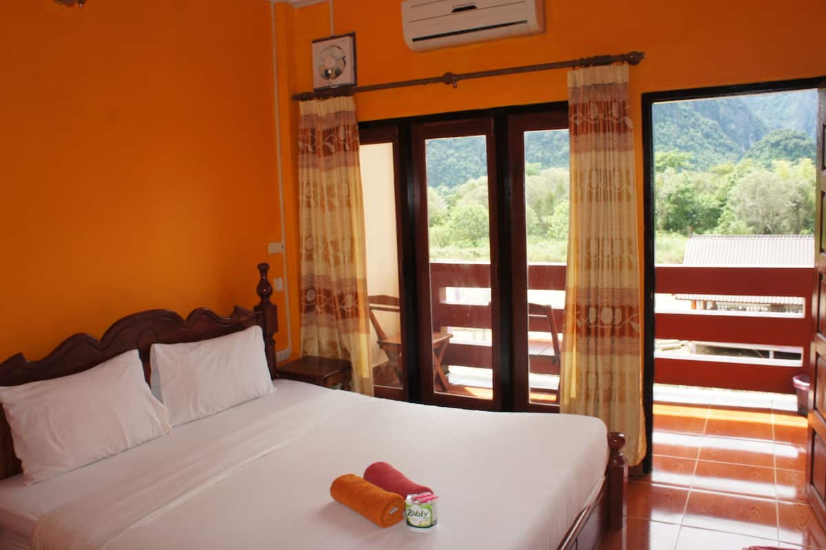 A hotel room with a bed, a small table, and a view of the outdoors.