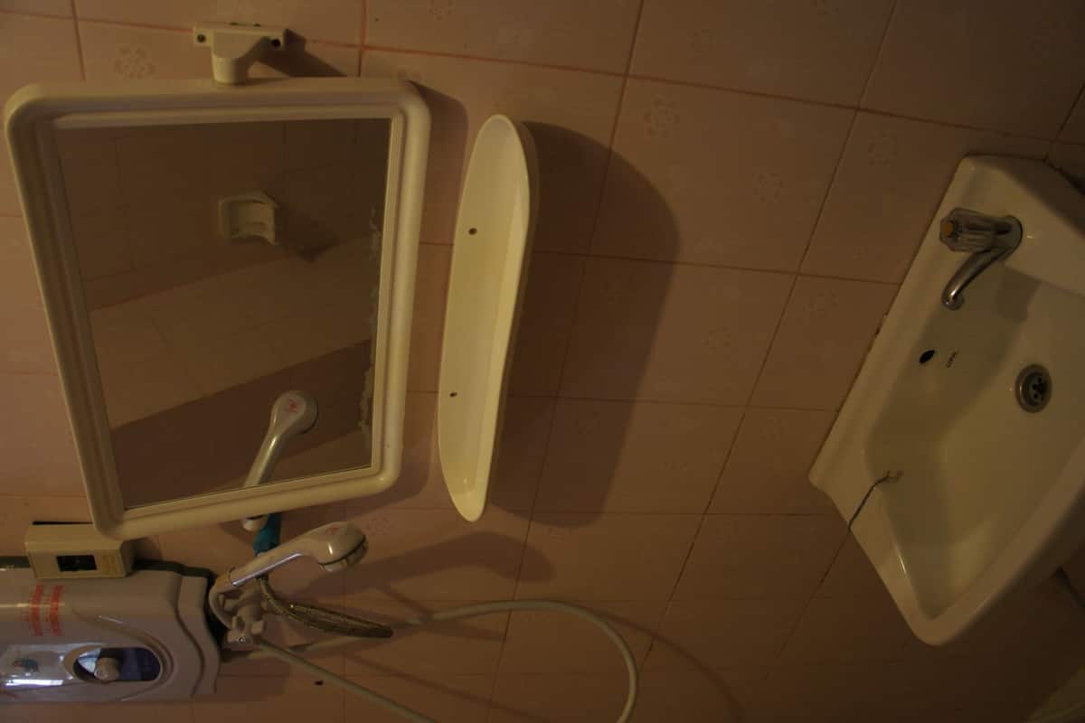 A bathroom with a sink, mirror, and handheld showerhead.