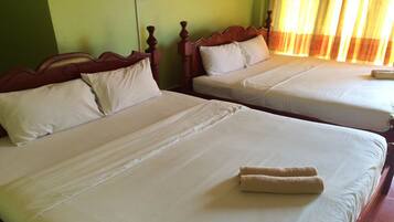 Two twin beds with wooden headboards, white linens, and a rolled towel on the bed.