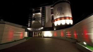 Entrada de hotel con diseño moderno, destacando una estructura cilíndrica con el nombre del hotel.
