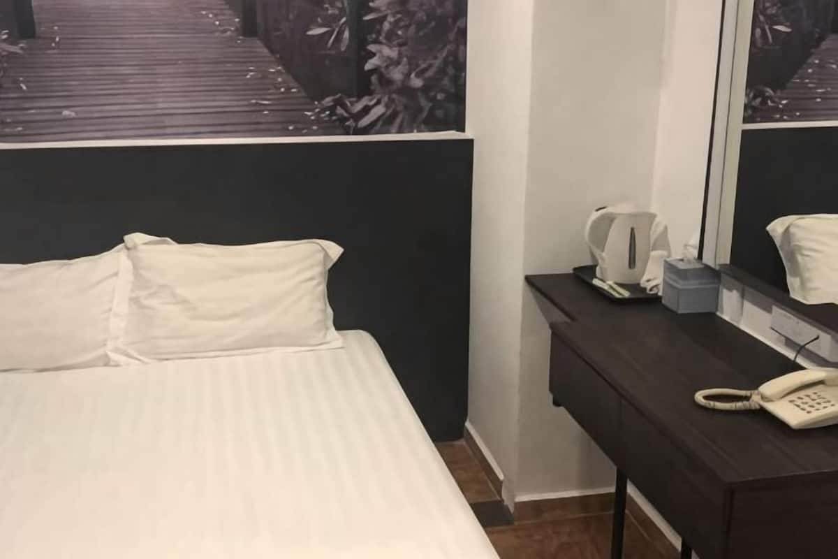 Quarto de hotel com uma cama, mesa de cabeceira com telefone, espelho e janela com vista para um deck de madeira.