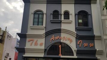 A hotel named "The Amazing Inn" with a modern facade, large windows, and a prominent entrance.