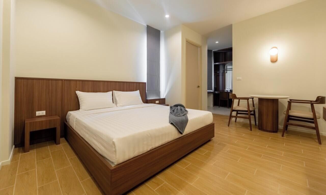 Habitación de hotel con una cama grande, mesitas de noche, un escritorio con sillas y un baño visible a través de una puerta abierta.