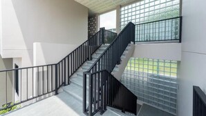 A multi-level interior with a staircase, glass railings, and a ceiling with a grid pattern. - The Regent Studio Kamala (Kamala)