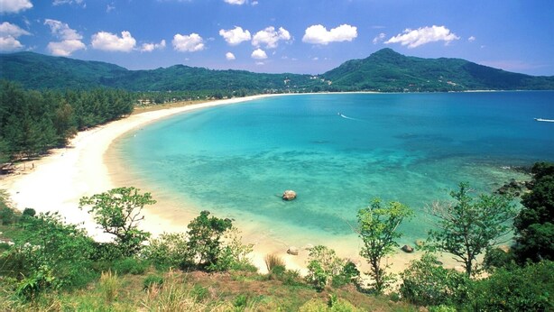 A coastal landscape with a sandy beach, clear turquoise waters, and lush green hills in the background. - The Regent Studio Kamala (Kamala)