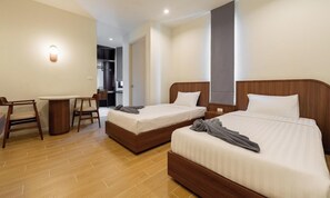 Ein Hotelzimmer mit zwei Betten, einem Schreibtisch und einem Stuhl.