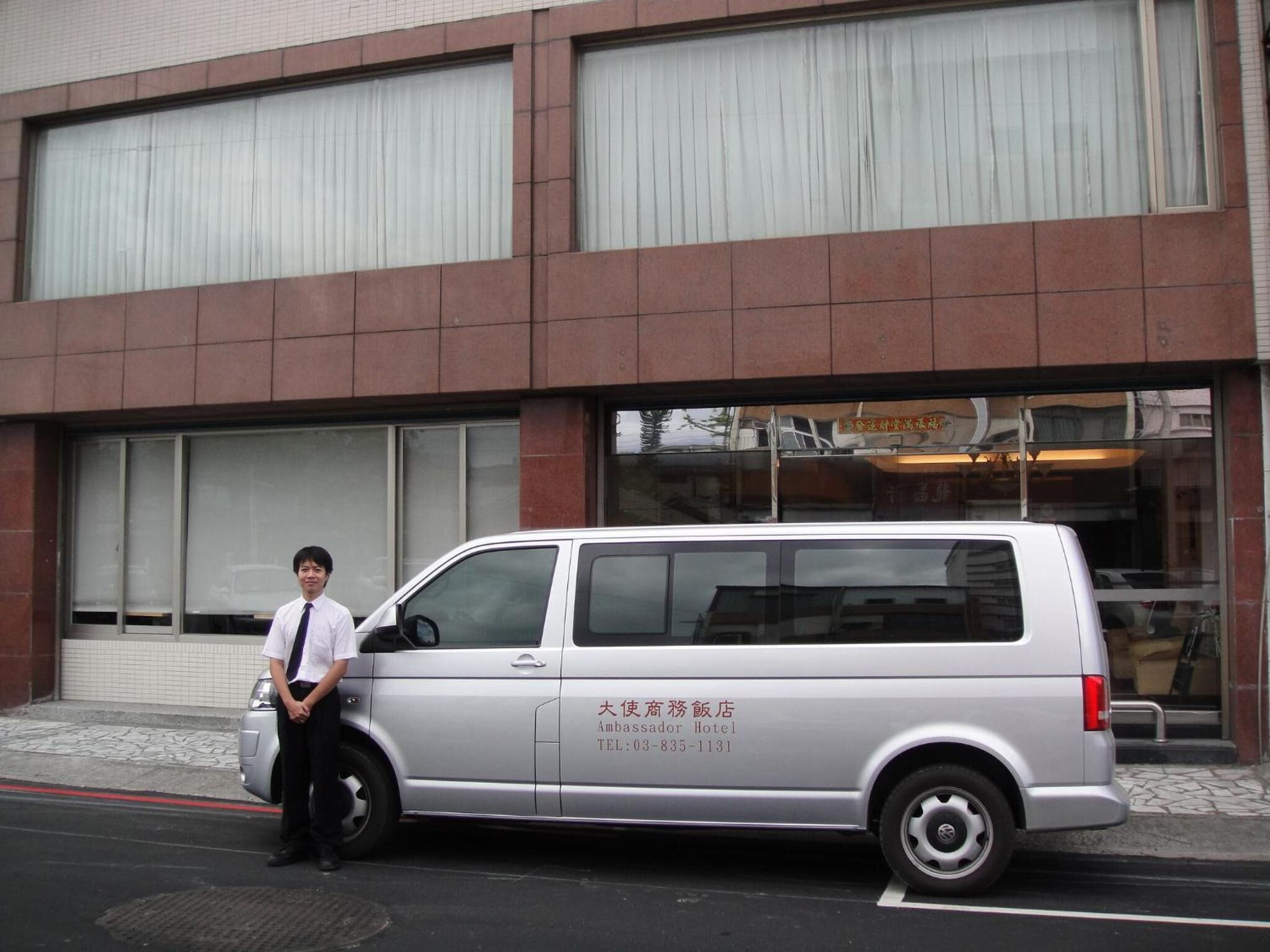 Una camioneta plateada estacionada frente a un edificio con ventanas grandes y fachada de azulejos.