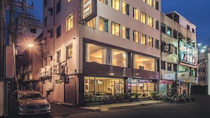 Un hôtel à plusieurs étages, doté d’une enseigne lumineuse, de grandes fenêtres et d’une façade bien éclairée.