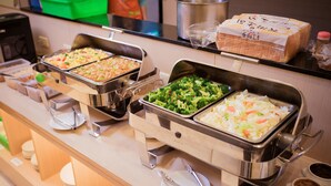 Un buffet proposant une variété de plats, notamment des salades, des légumes et du pain.