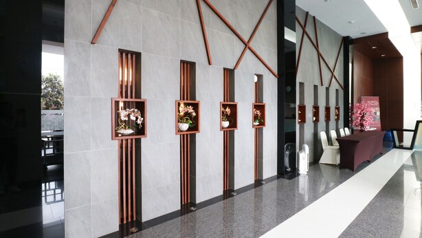 A modern lobby with a reception desk, seating area, and decorative plant shelves. - Ramedo Hotel (Makassar)