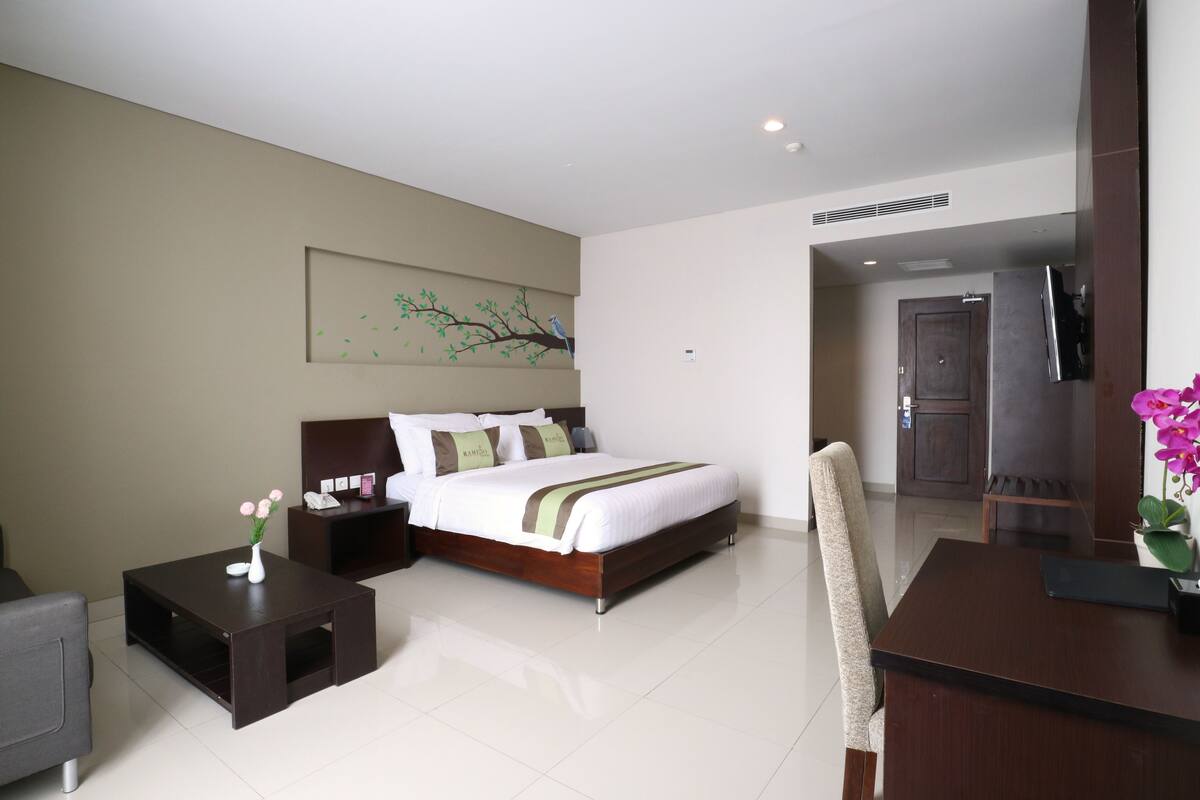 A hotel room with a bed, bedside tables, a desk, and a chair.