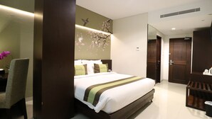A modern hotel room with a large bed, a desk, and a chair. - Ramedo Hotel (Makassar)