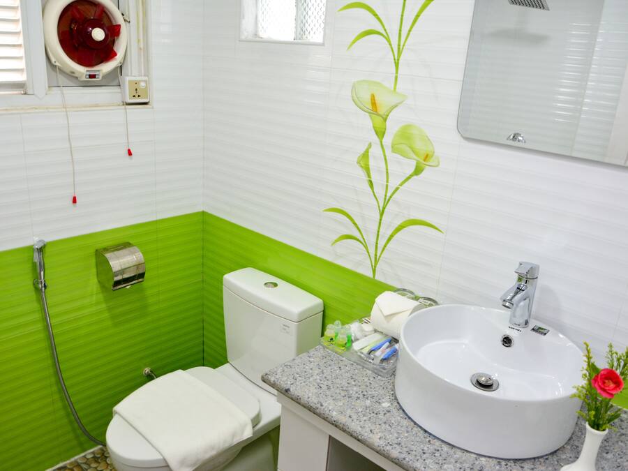 Un baño con lavamanos blanco, un espejo, un inodoro y una pared de acento verde.