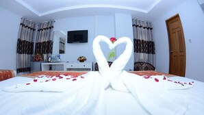 Una habitación de hotel con una cama, un escritorio, un televisor y una puerta.