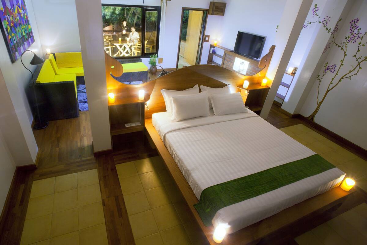 A hotel room with a bed, bedside tables, a desk, and a television.