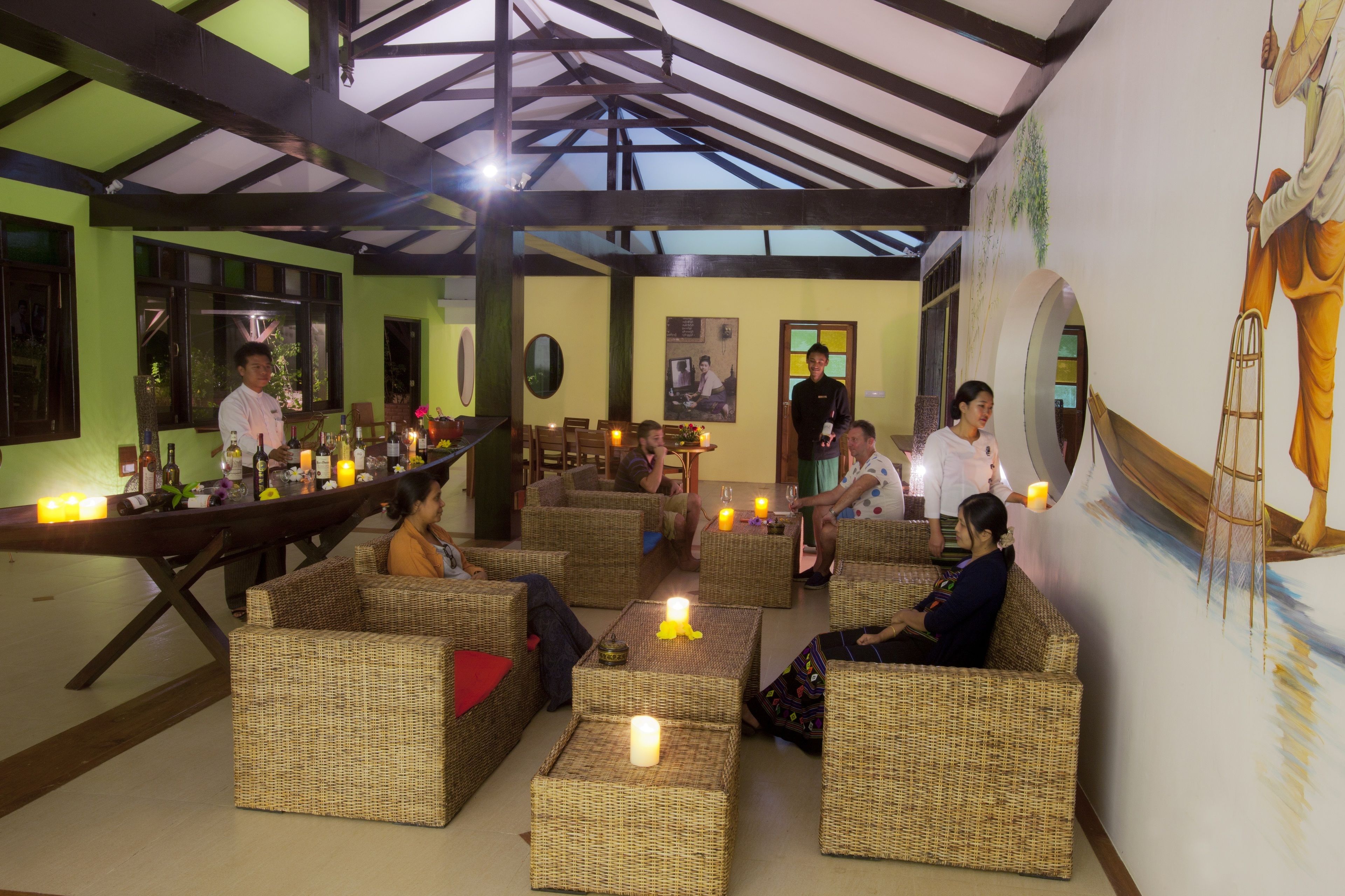 A room with wicker furniture, candles, and a mural.