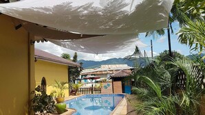 Un espace piscine doté de chaises longues et d’un auvent ombragé.