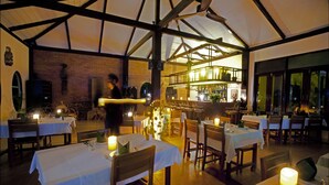 Un restaurant avec des tables dressées pour le service, un coin bar et un mur en briques.