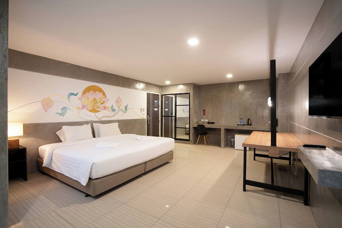 A modern hotel room with a large bed, a desk, and a television.