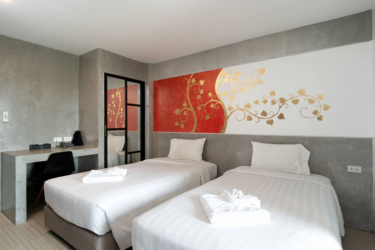 A hotel room with two beds, a desk, and a large decorative wall mural.