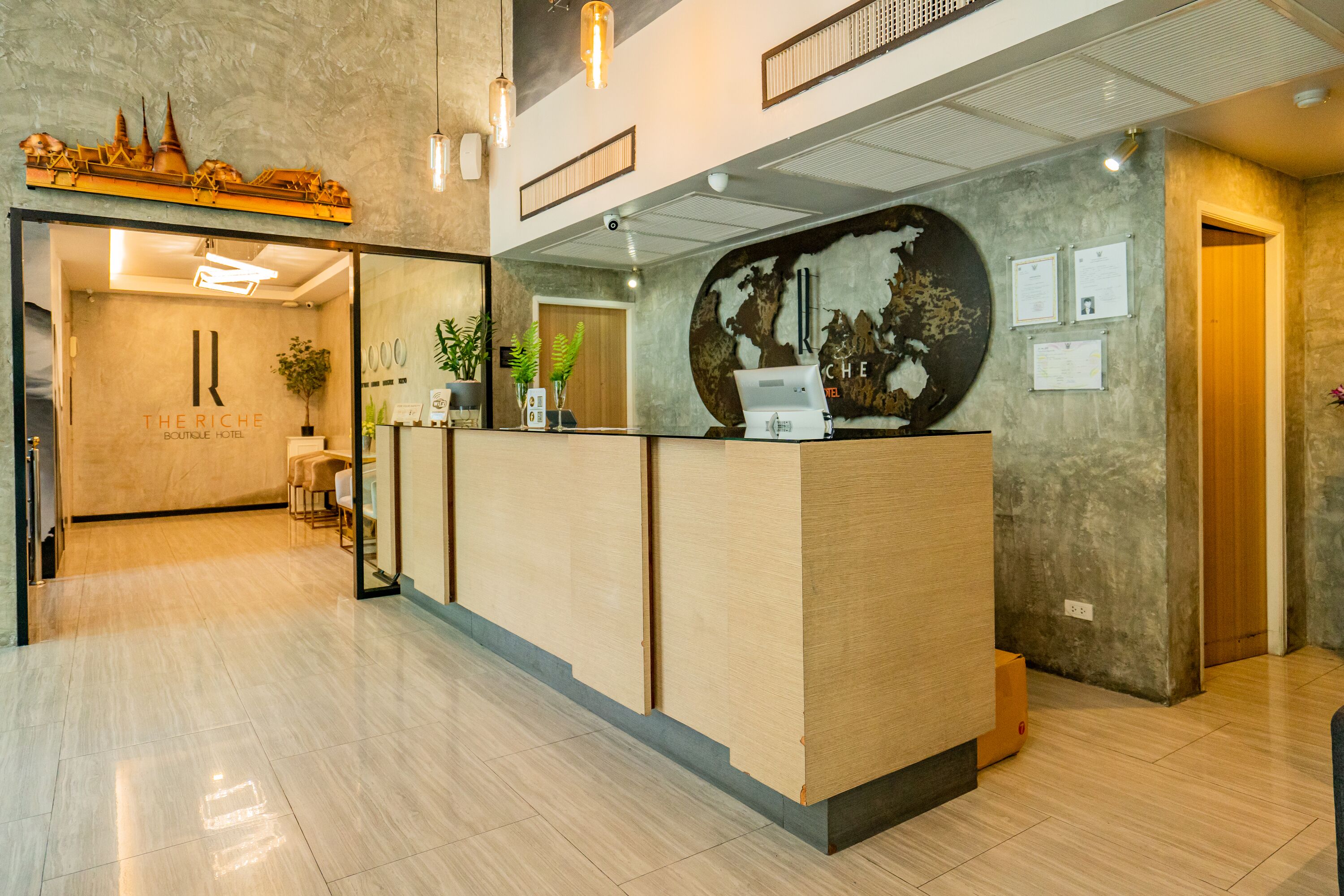 Zona de recepción de hotel con un mostrador de madera, un mural de un gran mapa mundial y un diseño de interiores moderno.
