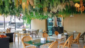 A restaurant with indoor seating, tables, chairs, and hanging greenery.